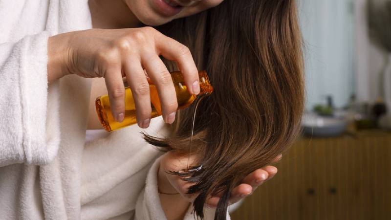 Mujer poniéndose aceite en el cabello.