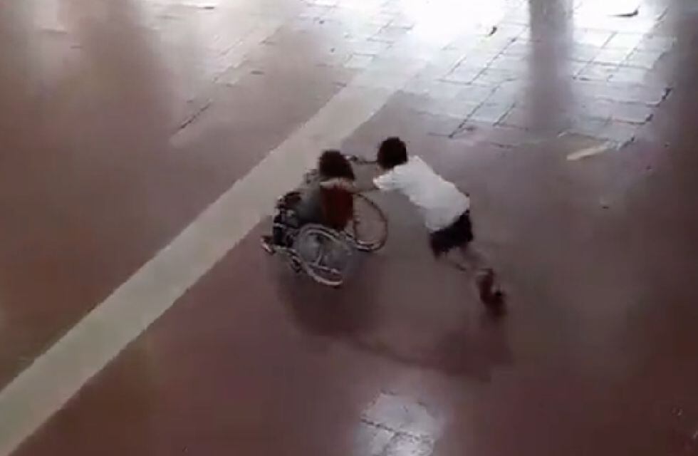 Niño demuestra solidaridad con su compañero en silla de ruedas.