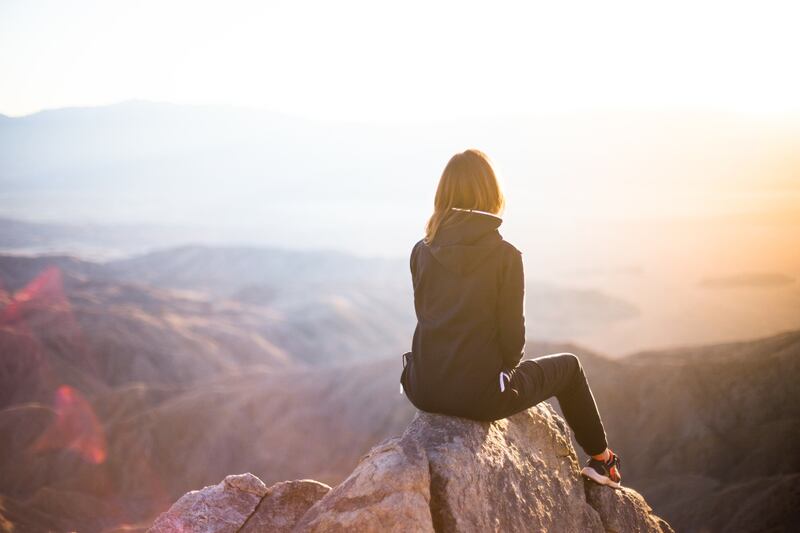 Mujer sentada en una roca mirando el horizonte.