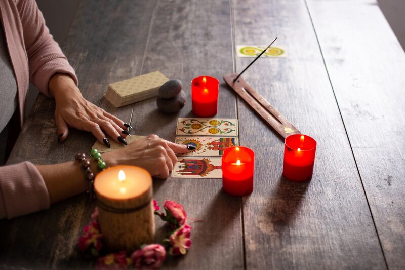 Persona viendo las cartas en una mesa rodeada de velas.