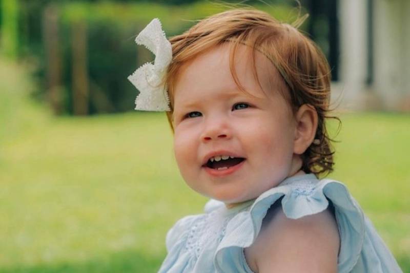 Primer plano de la sonriente cara de la princesa Lilibet Diana, siendo un bebé.