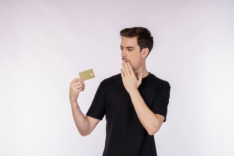 Hombre mirando con cara de sorprendido la tarjeta que sostiene en su mano.