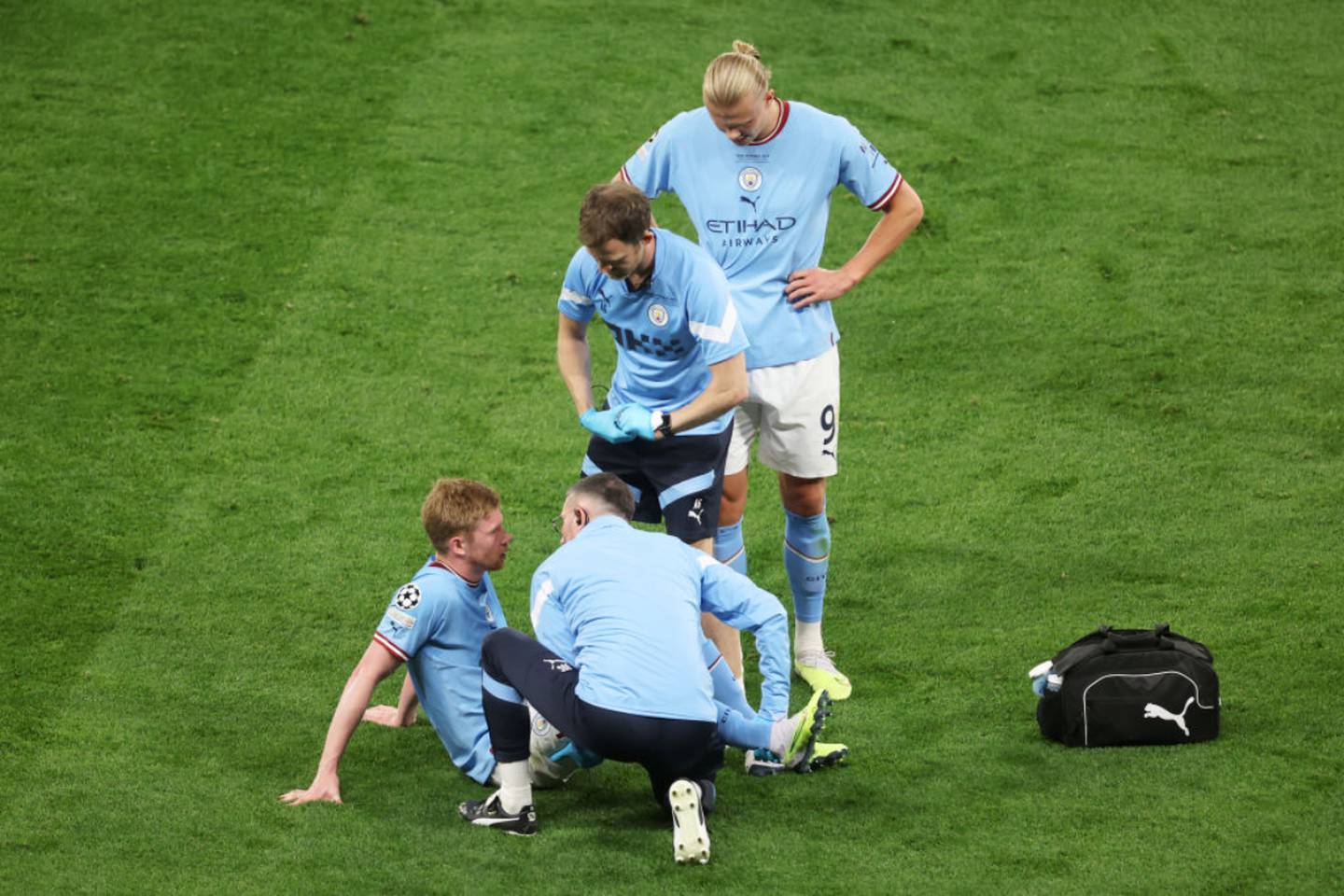 El delantero Kevin de Bruyne, recibe atención médica durante la final de la Champions League, mientas su compañero de equipo Erling Haaland observa.