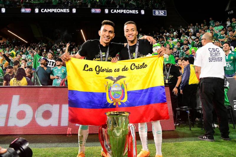Los futbolistas ecuatorianos Ángel Mena y Byron Castillo sosteniendo la bandera de Ecuador tras ganar la Liga de Campeones de Concacaf con el Club León.
