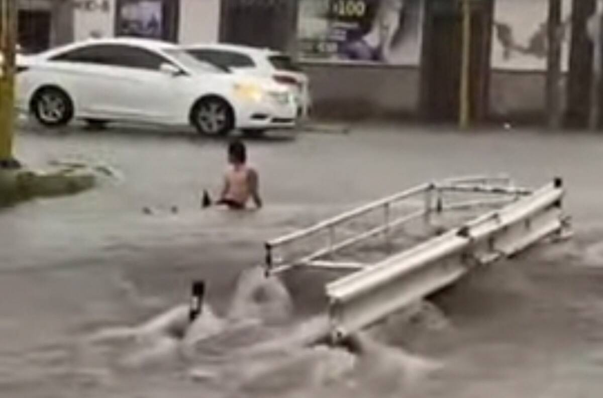 Un hombre disfruta de su cerveza en medio de una calle inundada