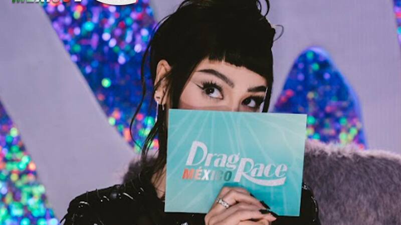 Mujer tapándose la cara coquetamente con el pelo negro, la chasquilla cortada y el pelo amarrado, se pasa la cara con una tarje con el nombre del programa.