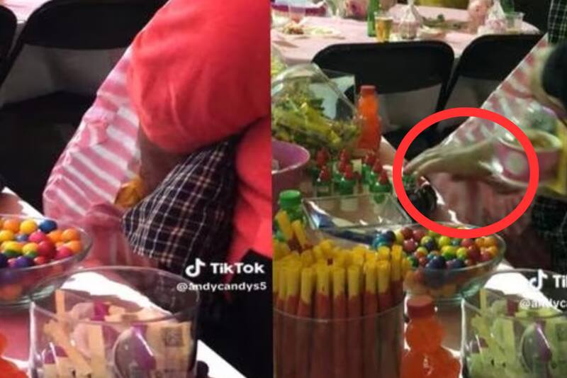 Captan a una señora agarrando gran cantidad de golosinas de la mesa de dulces.