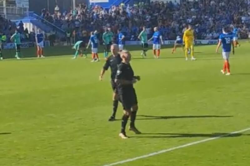 El hincha calentando para asumir cono juez de línea en partido entre Portsmouth y Cheltenham