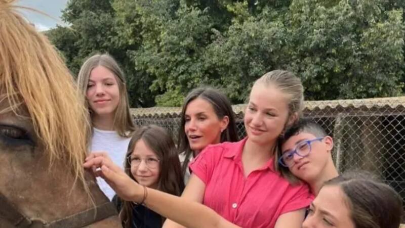 La reina Letizia y sus hijas, acompañadas de un grupo de niños, durante la visita este viernes a la Granja Escola Jovent.