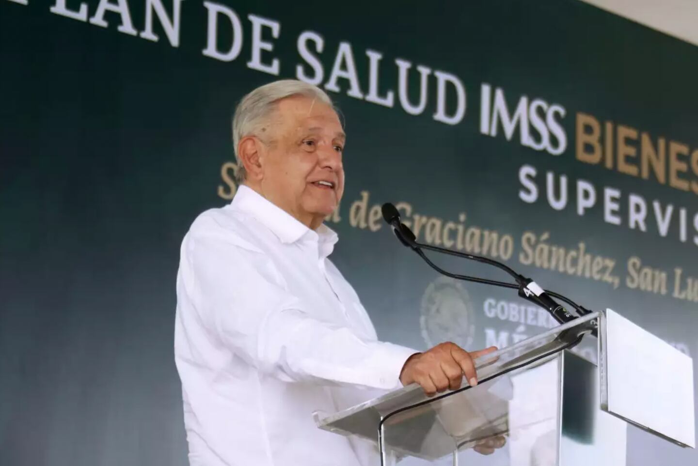 El presidente de México vestido con camisa blanca hablando en conferencia y viendo al público.
